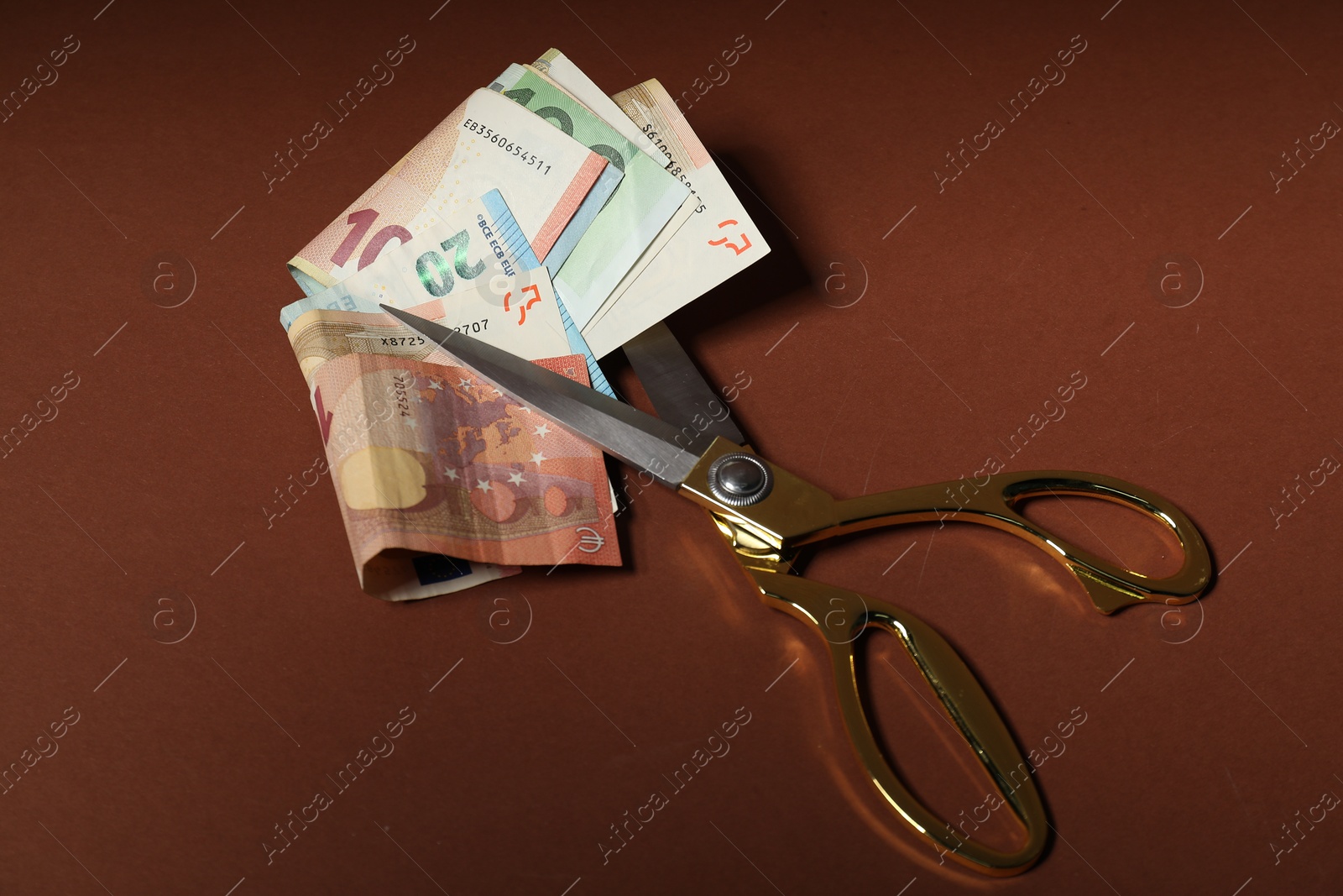 Photo of Euro banknotes and scissors on brown background