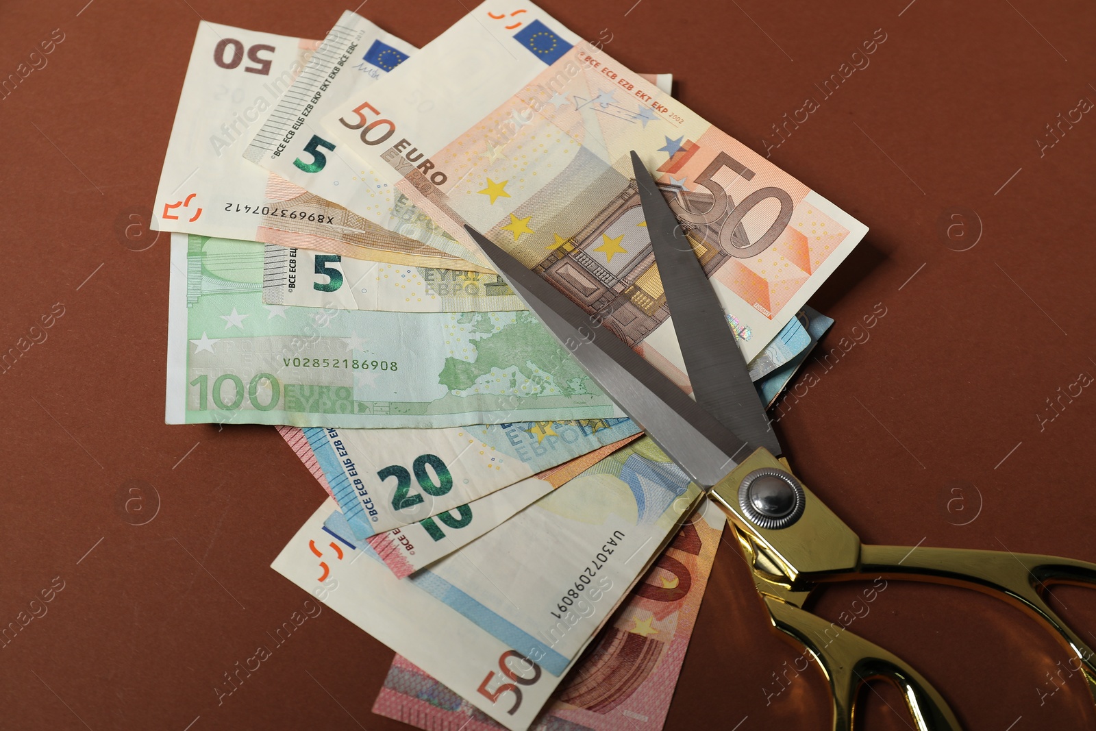 Photo of Euro banknotes and scissors on brown background