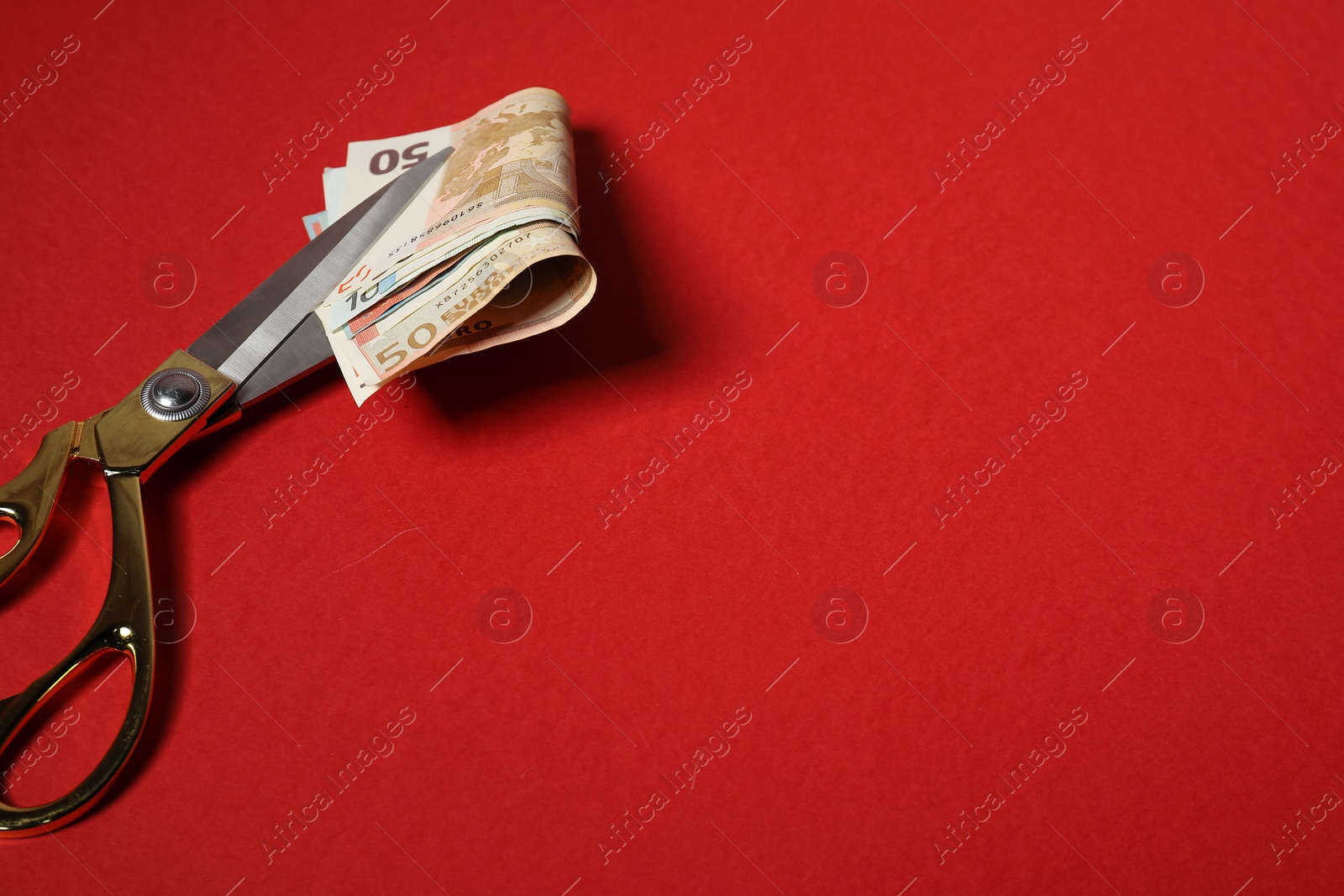 Photo of Euro banknotes and scissors on red background, space for text