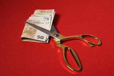 Photo of Euro banknotes and scissors on red background