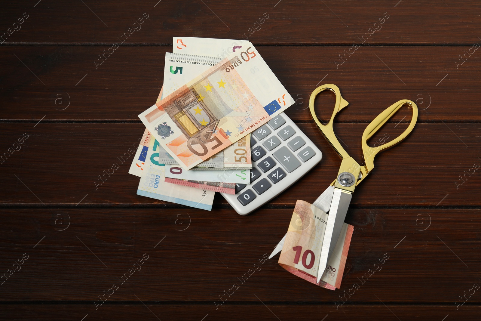 Photo of Euro banknotes, scissors and calculator on wooden table, flat lay