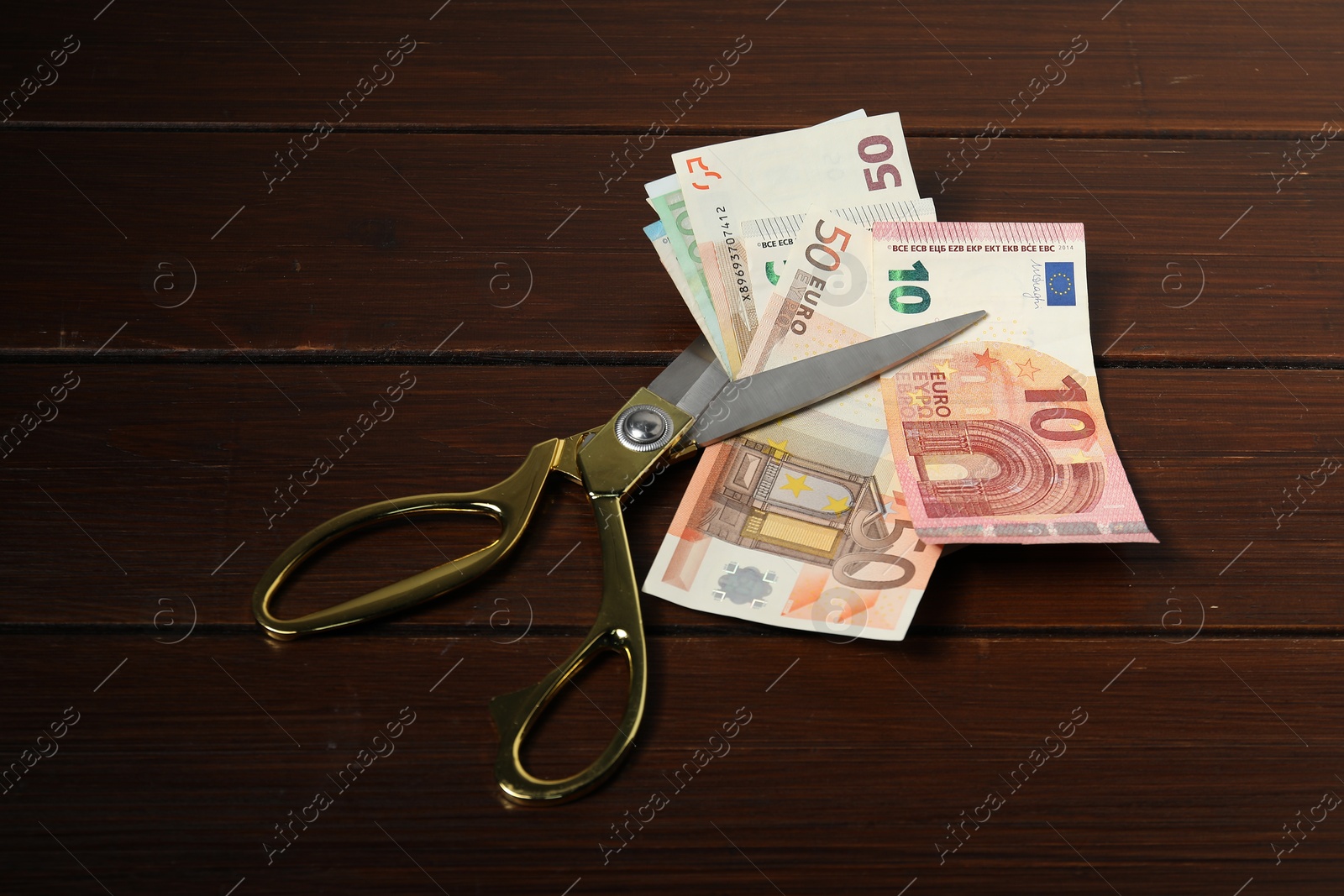 Photo of Euro banknotes and scissors on wooden table