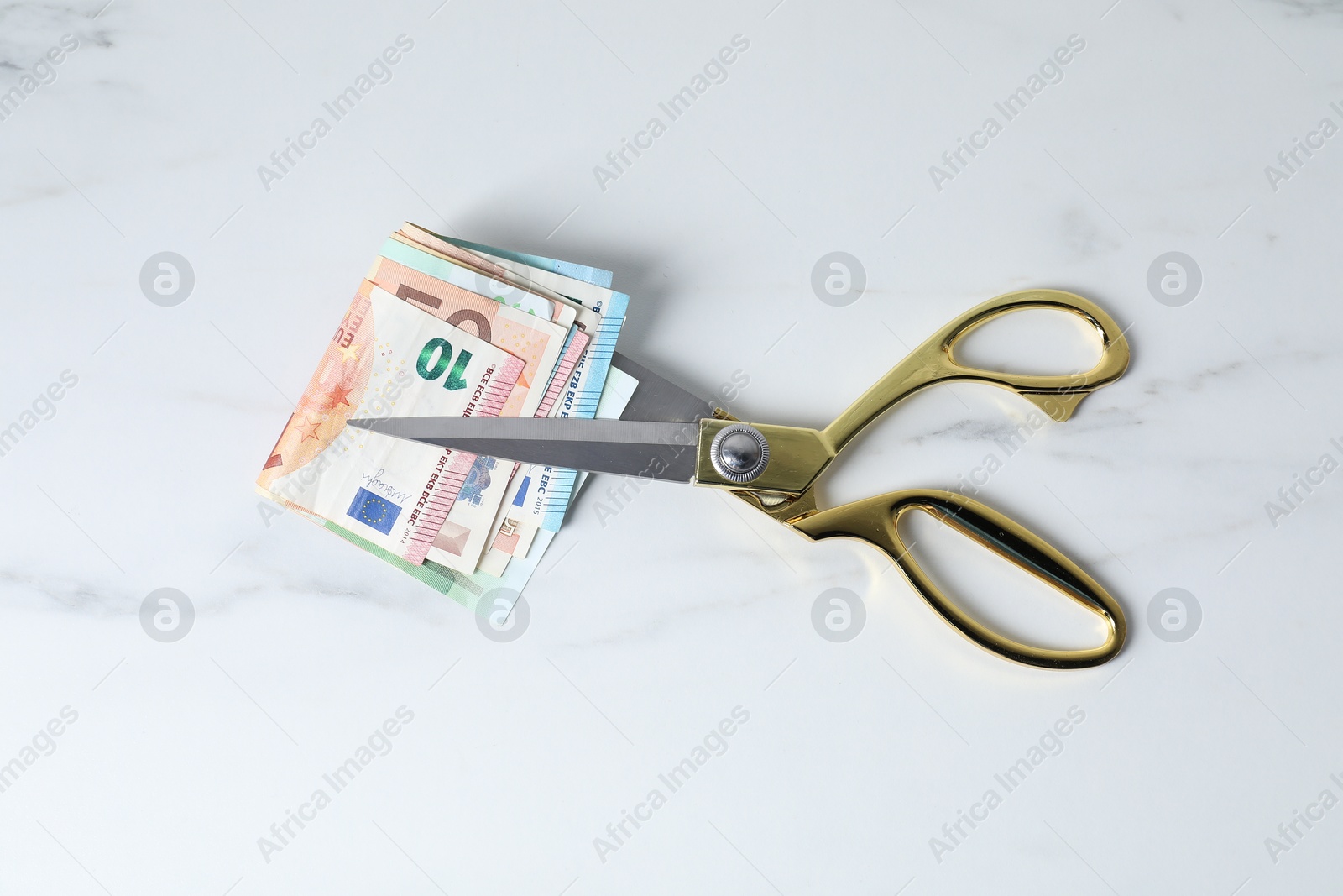 Photo of Euro banknotes and scissors on light marble table, top view