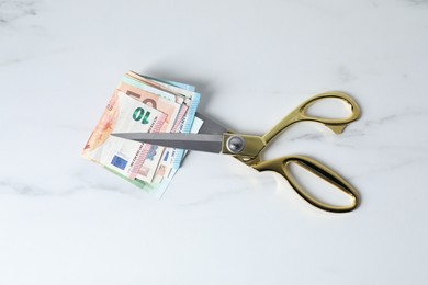 Photo of Euro banknotes and scissors on light marble table, top view