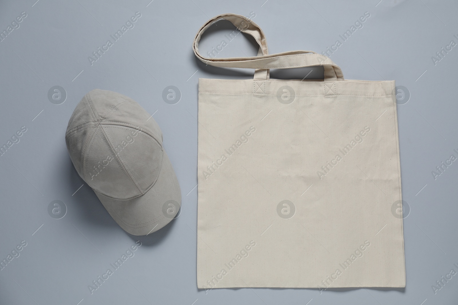 Photo of Blank shopping bag and cap for branding on gray background, flat lay. Mockup for design