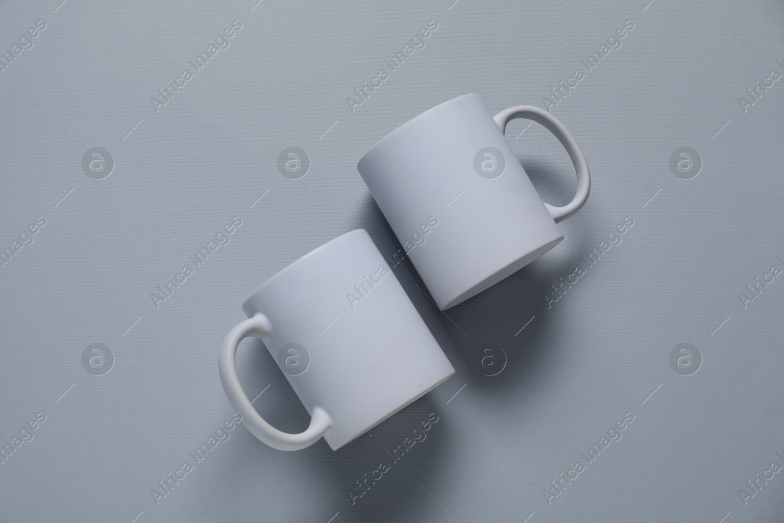 Photo of Blank cups for branding on gray background, flat lay. Mockup for design