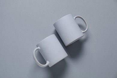 Photo of Blank cups for branding on gray background, flat lay. Mockup for design