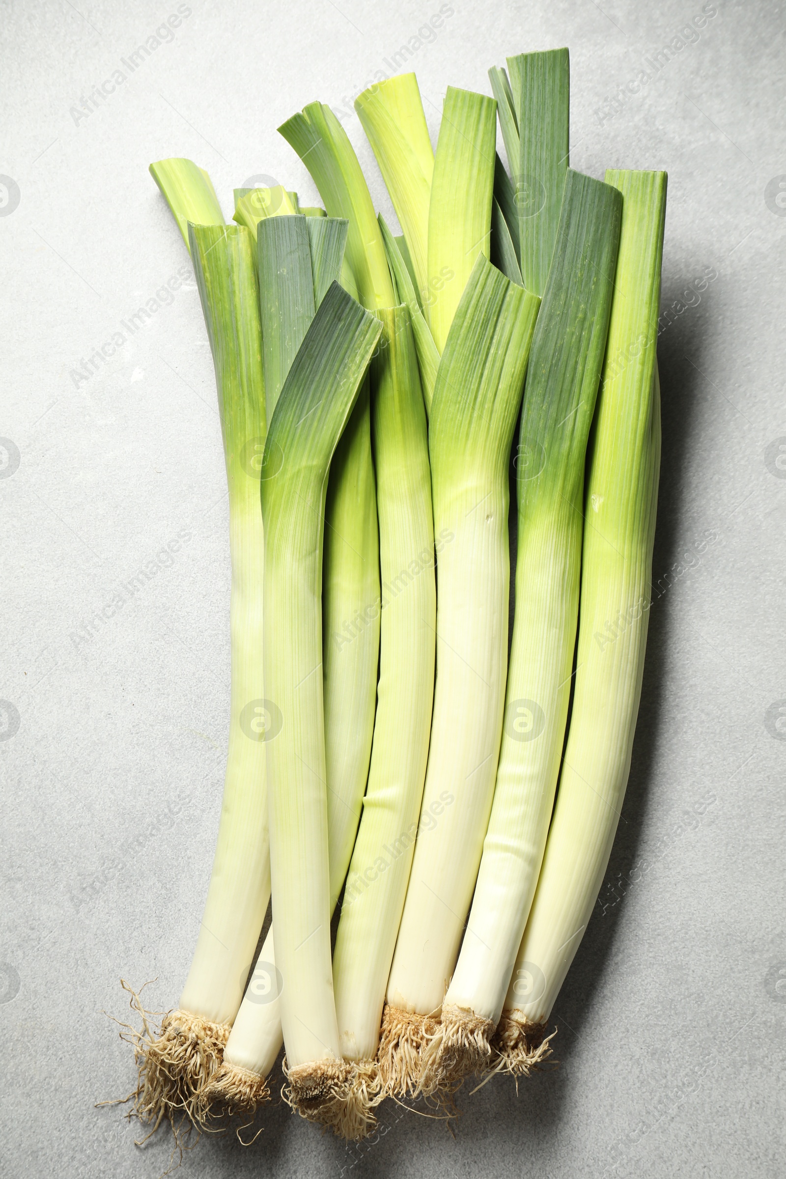 Photo of Fresh green leeks on light grey table, top view