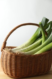 Photo of Fresh leeks in basket on wooden table