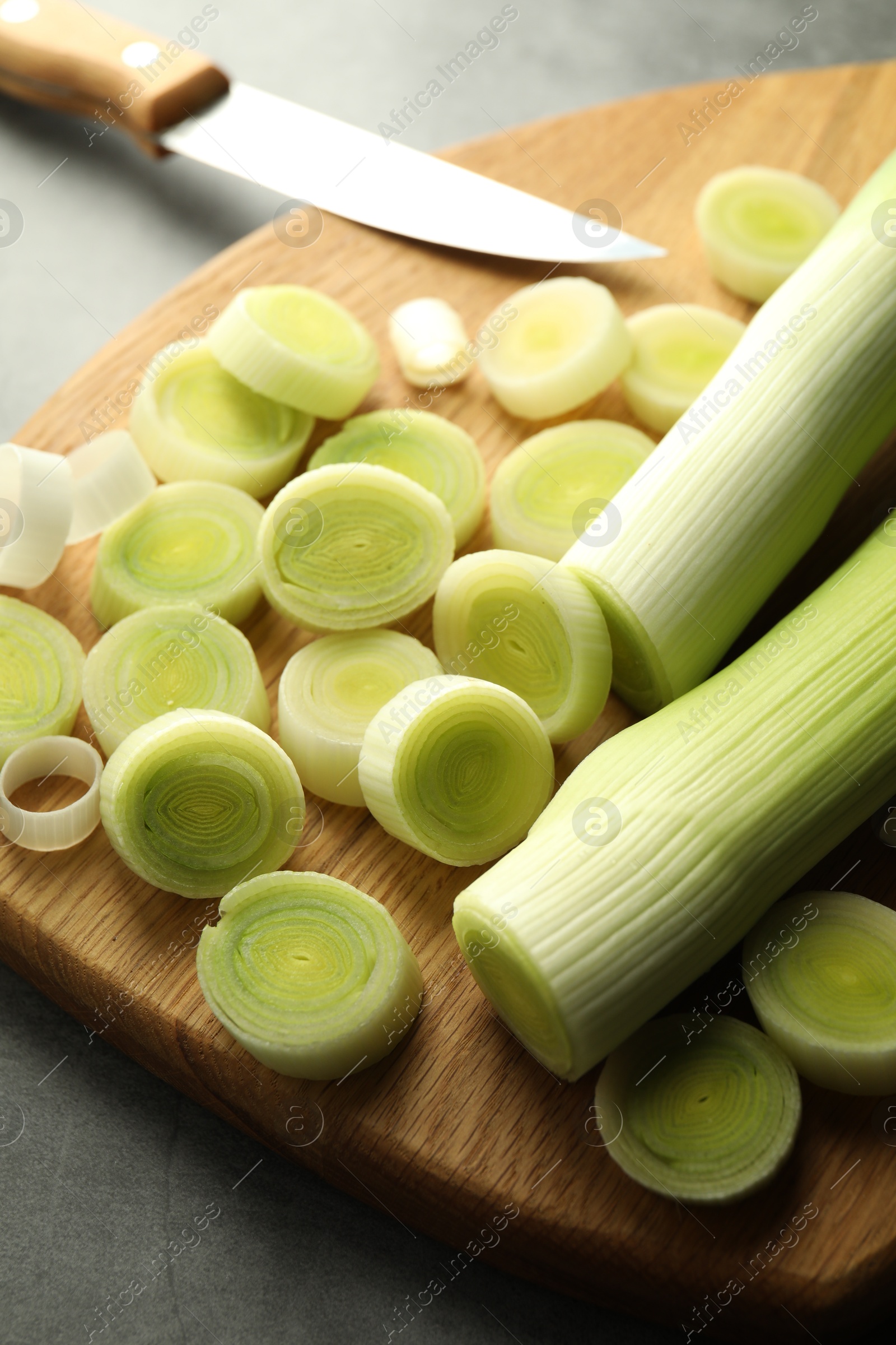 Photo of Chopped leeks and knife on grey table, closeup