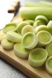 Photo of Chopped leeks and knife on grey table, closeup