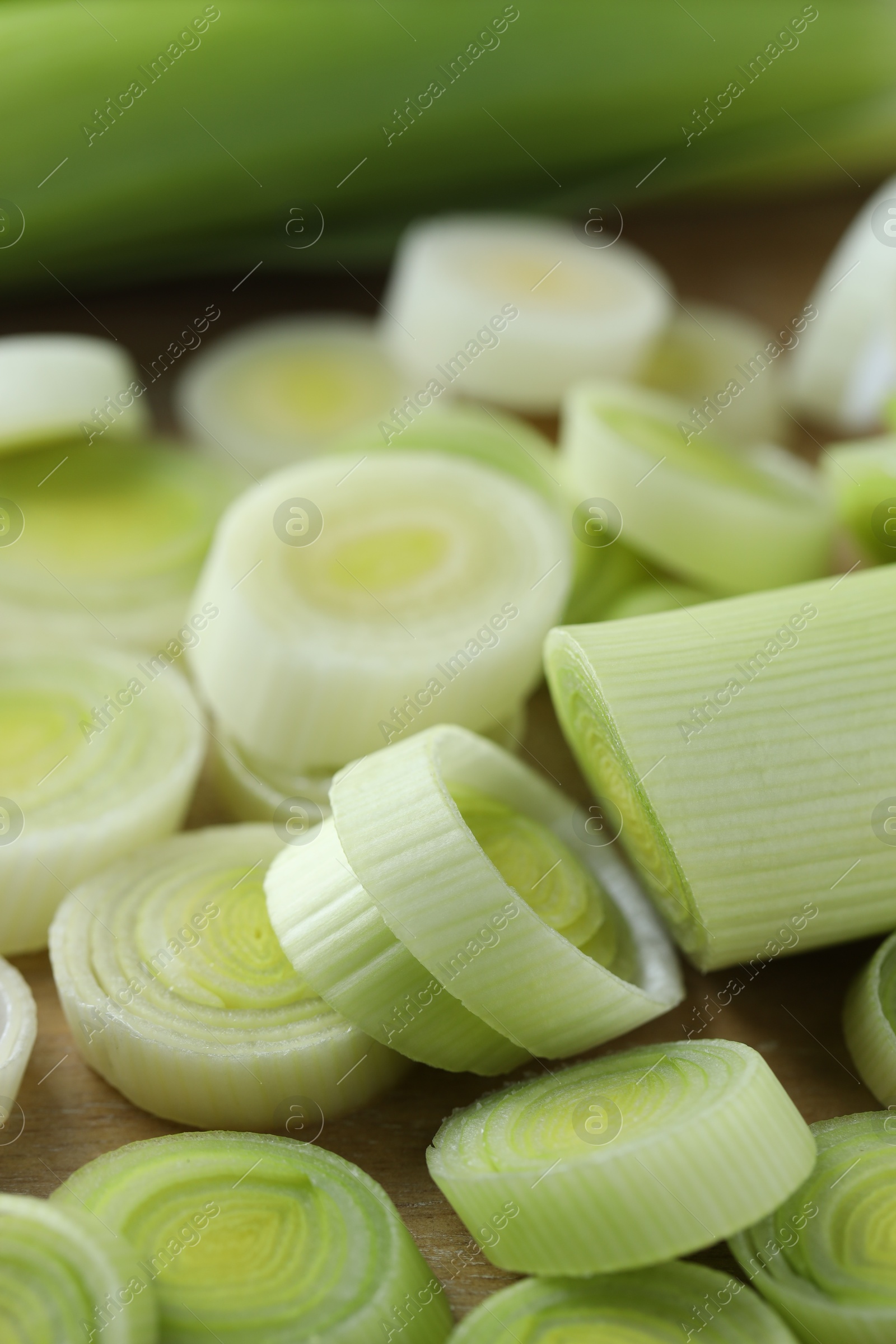 Photo of Fresh chopped leeks on wooden board, closeup