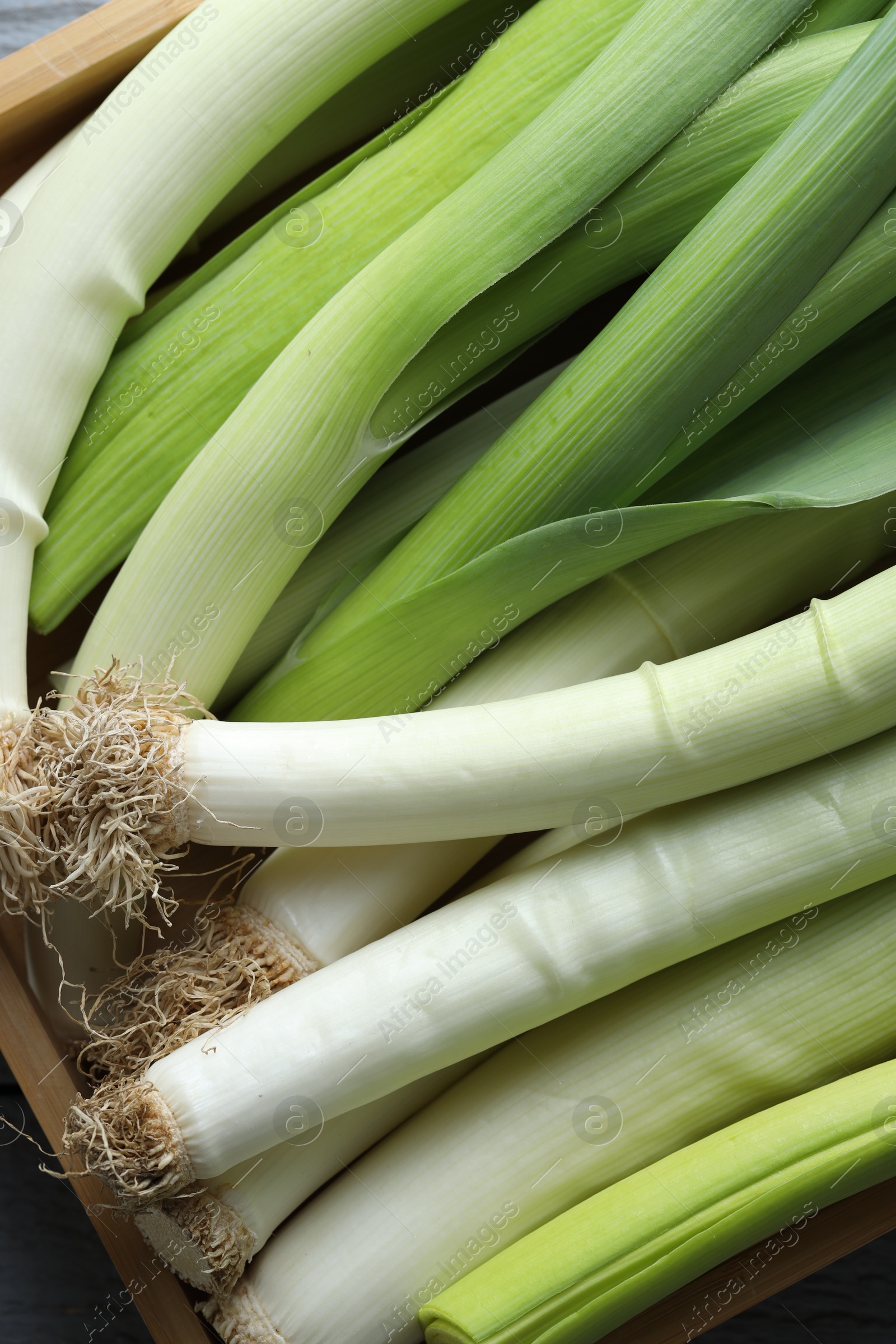 Photo of Fresh leeks in crate on table, top view