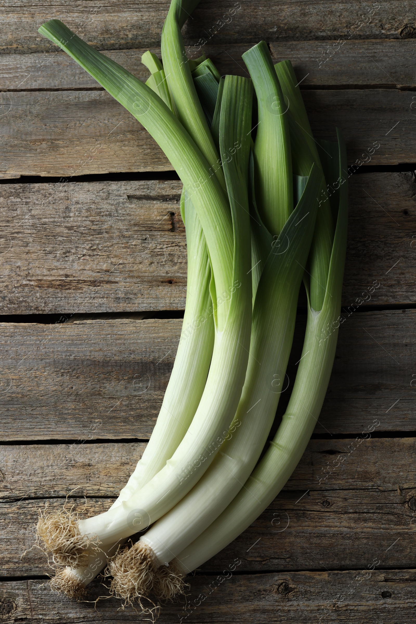 Photo of Whole fresh leeks on wooden table, top view