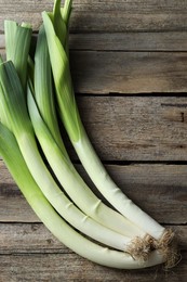 Photo of Whole fresh leeks on wooden table, top view