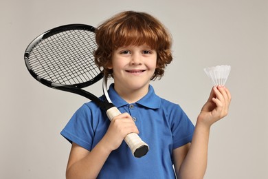 Photo of Little boy with badminton racket and shuttlecock on light grey background