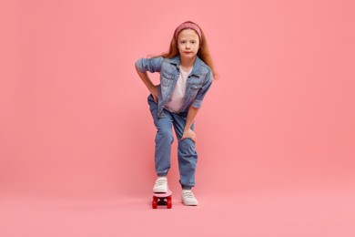 Photo of Little girl with penny board on pink background