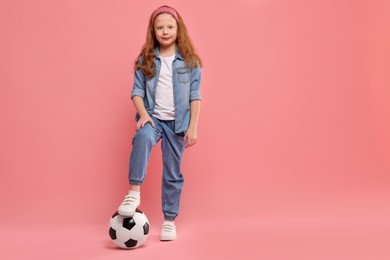 Photo of Little girl with soccer ball on pink background, space for text