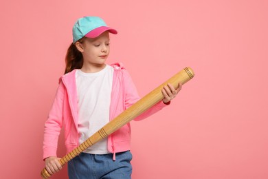 Photo of Little girl with baseball bat on pink background, space for text