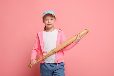 Photo of Little girl with baseball bat on pink background