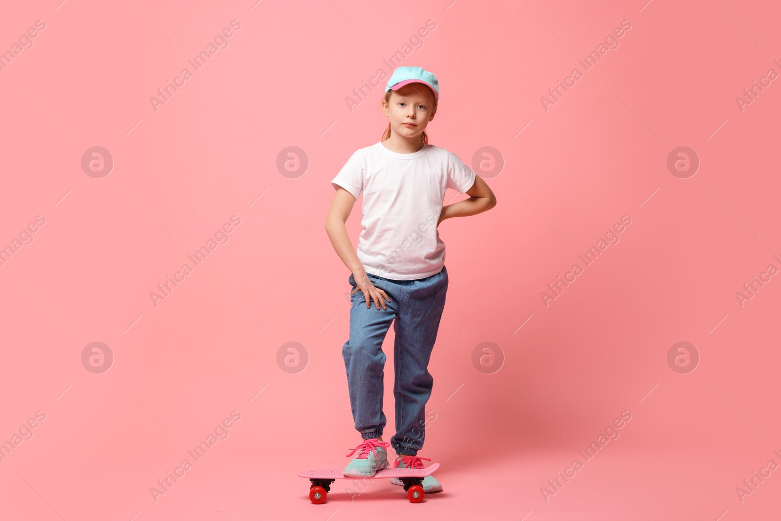 Photo of Little girl with penny board on pink background