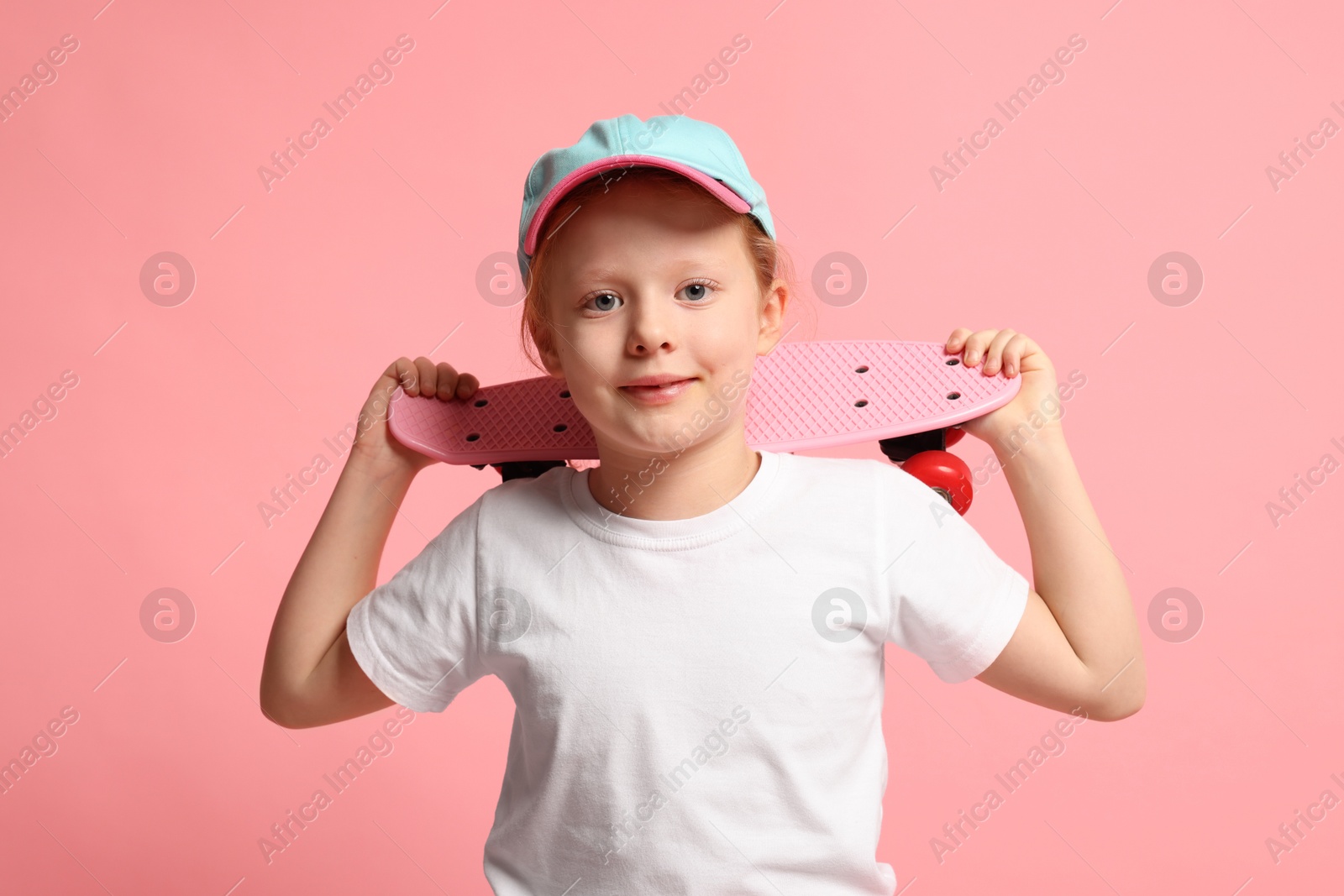 Photo of Little girl with penny board on pink background