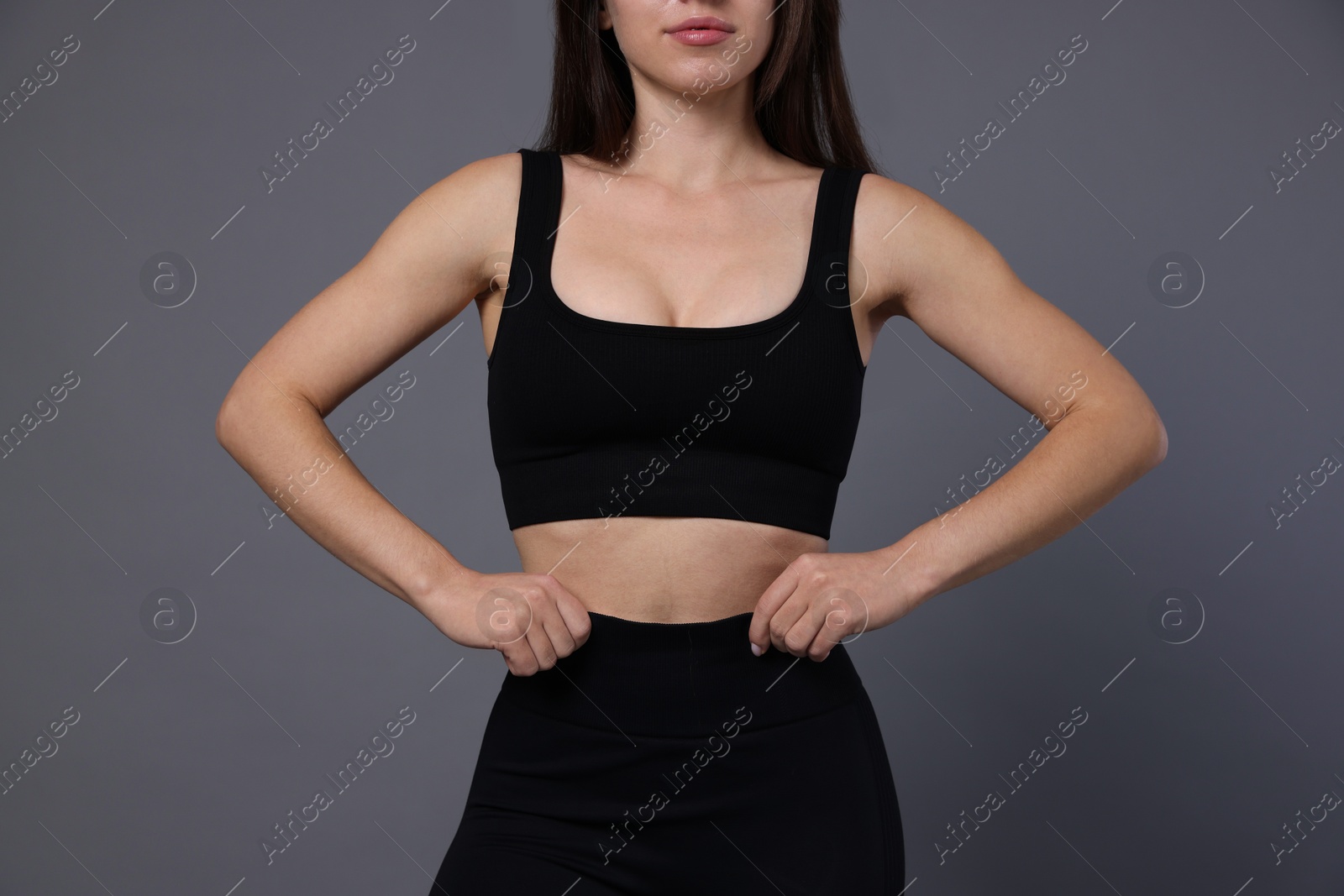 Photo of Woman in sportswear on grey background, closeup