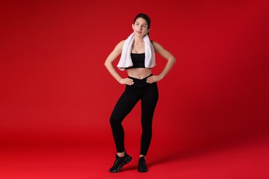 Photo of Woman in sportswear with towel on red background