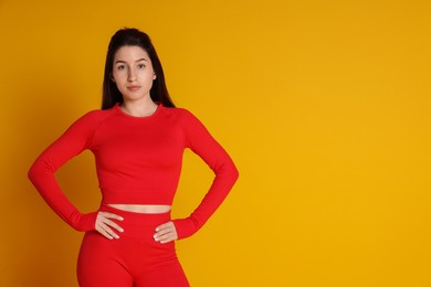 Portrait of woman in sportswear on orange background, space for text