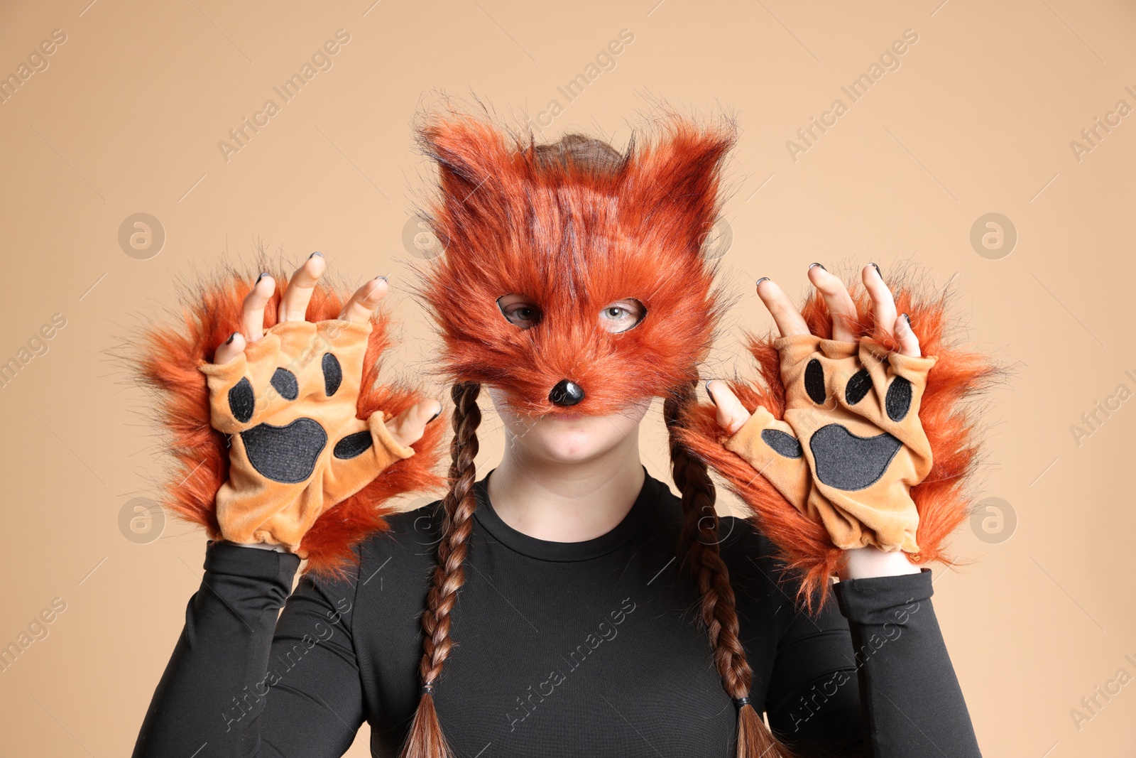 Photo of Quadrobics. Girl wearing fox mask and gloves on beige background