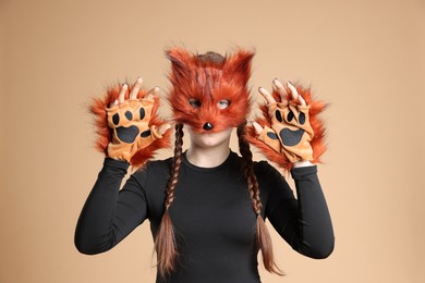 Photo of Quadrobics. Girl wearing fox mask and gloves on beige background