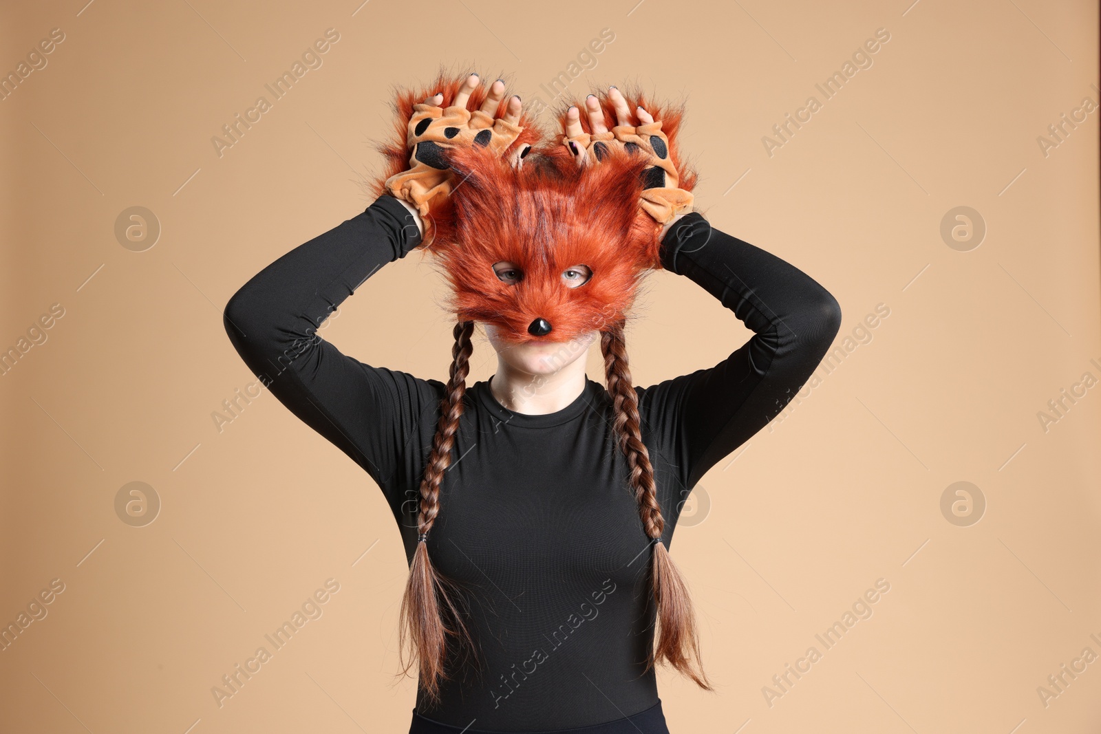 Photo of Quadrobics. Girl wearing fox mask and gloves on beige background