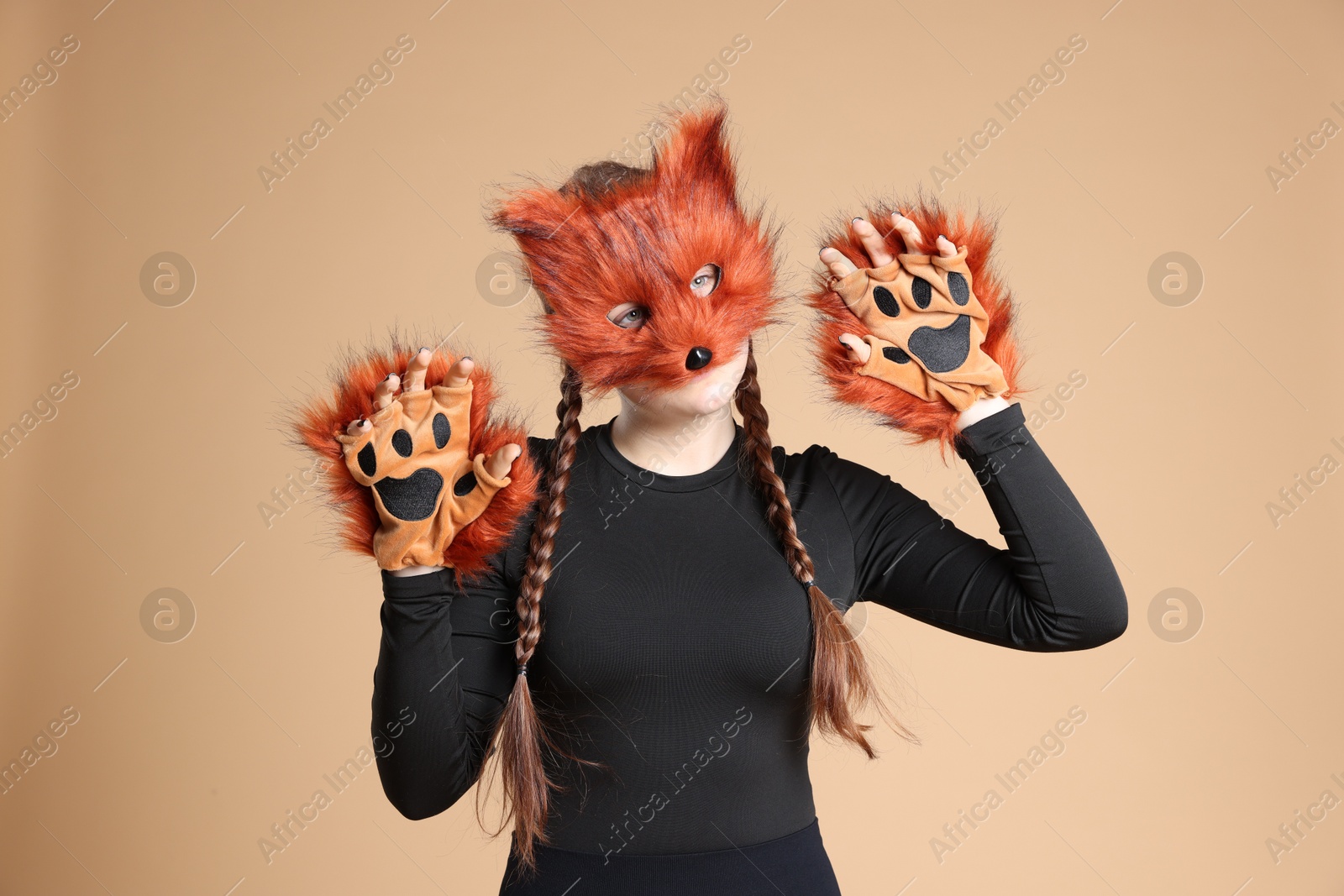 Photo of Quadrobics. Girl wearing fox mask and gloves on beige background