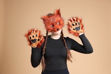 Photo of Quadrobics. Girl wearing fox mask and gloves on beige background