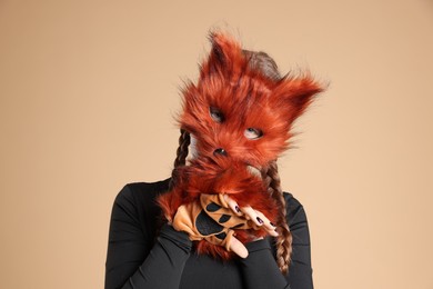 Photo of Quadrobics. Girl wearing fox mask and gloves on beige background