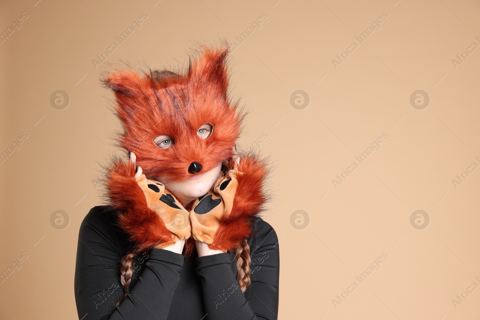 Photo of Quadrobics. Girl wearing fox mask and gloves on beige background, space for text