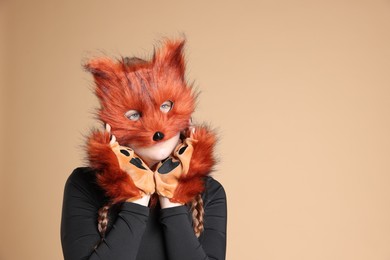 Photo of Quadrobics. Girl wearing fox mask and gloves on beige background, space for text