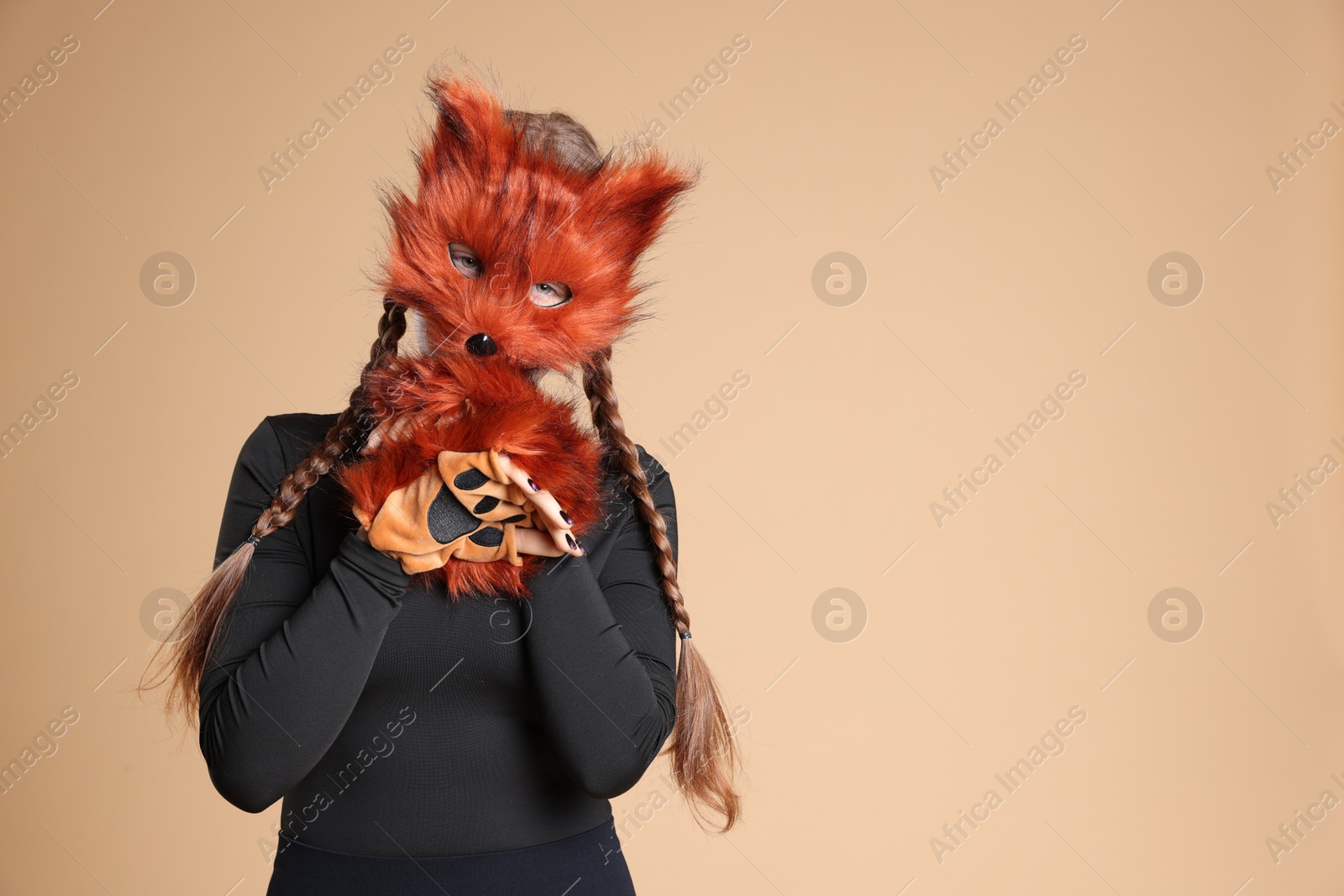 Photo of Quadrobics. Girl wearing fox mask and gloves on beige background, space for text