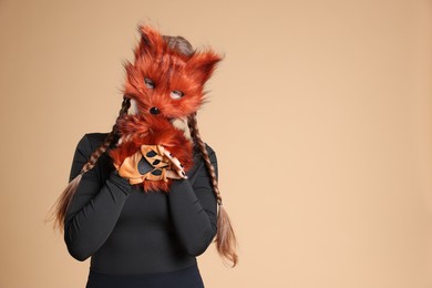 Photo of Quadrobics. Girl wearing fox mask and gloves on beige background, space for text