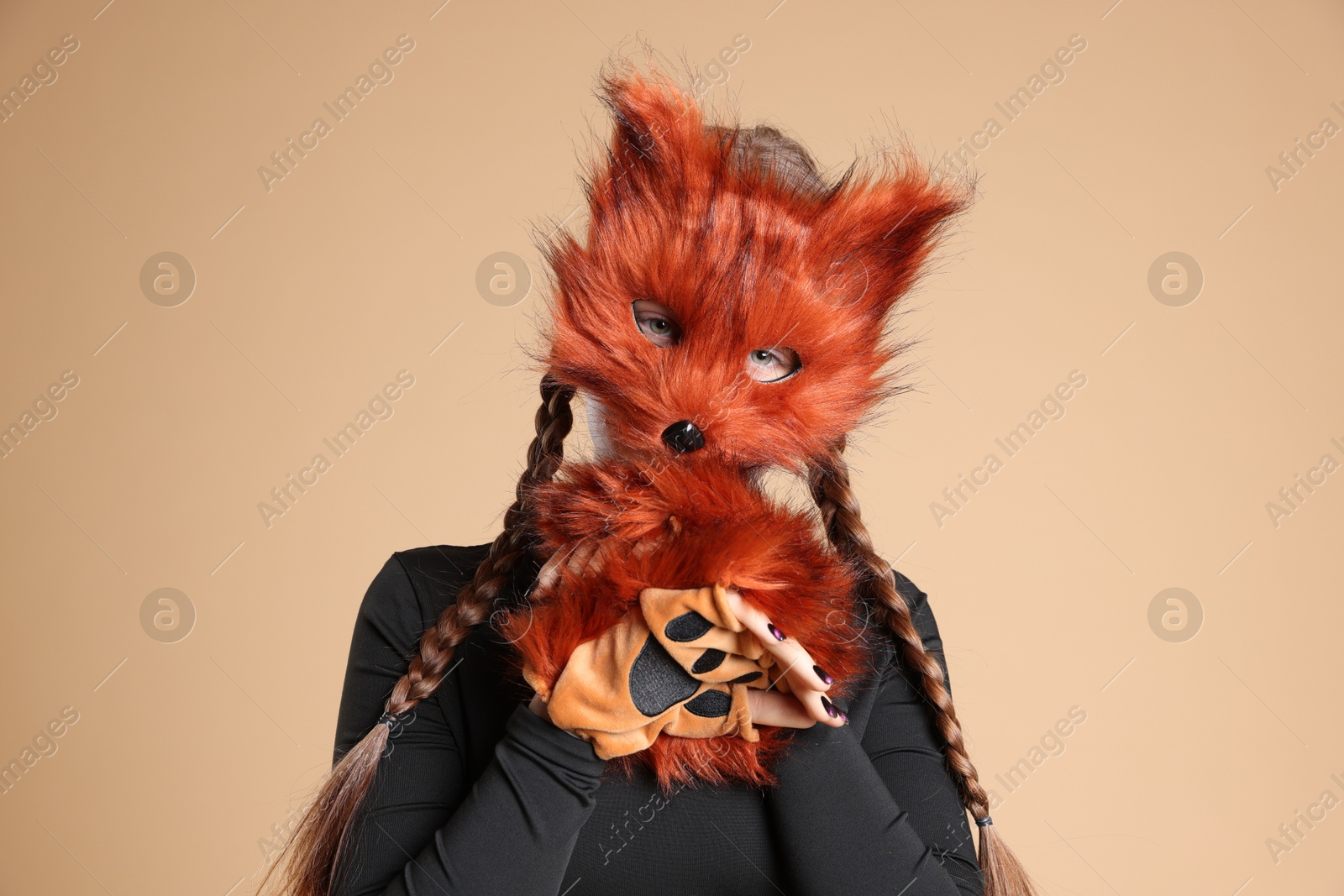 Photo of Quadrobics. Girl wearing fox mask and gloves on beige background