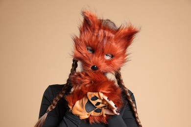 Photo of Quadrobics. Girl wearing fox mask and gloves on beige background