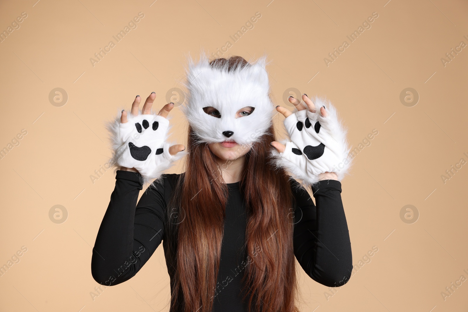 Photo of Quadrobics. Girl wearing cat mask and gloves on beige background