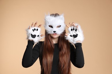 Photo of Quadrobics. Girl wearing cat mask and gloves on beige background