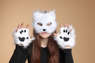 Photo of Quadrobics. Girl wearing cat mask and gloves on beige background