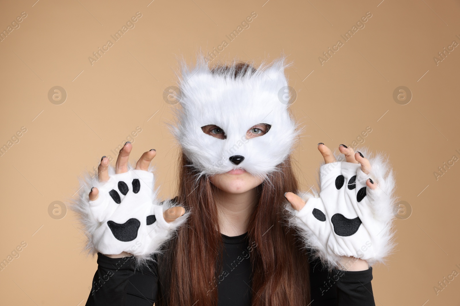 Photo of Quadrobics. Girl wearing cat mask and gloves on beige background