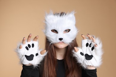 Photo of Quadrobics. Girl wearing cat mask and gloves on beige background