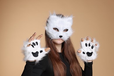 Photo of Quadrobics. Girl wearing cat mask and gloves on beige background