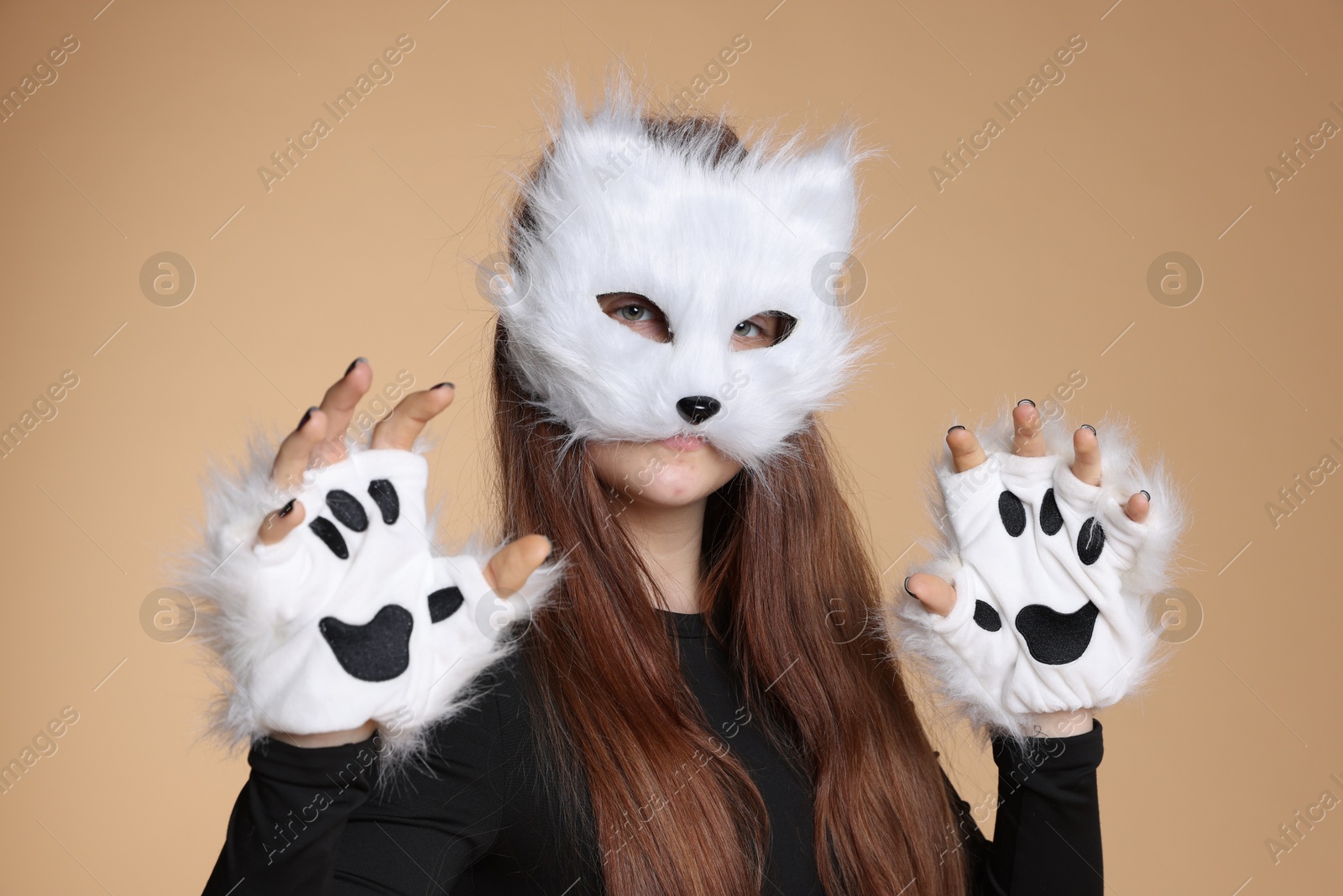 Photo of Quadrobics. Girl wearing cat mask and gloves on beige background