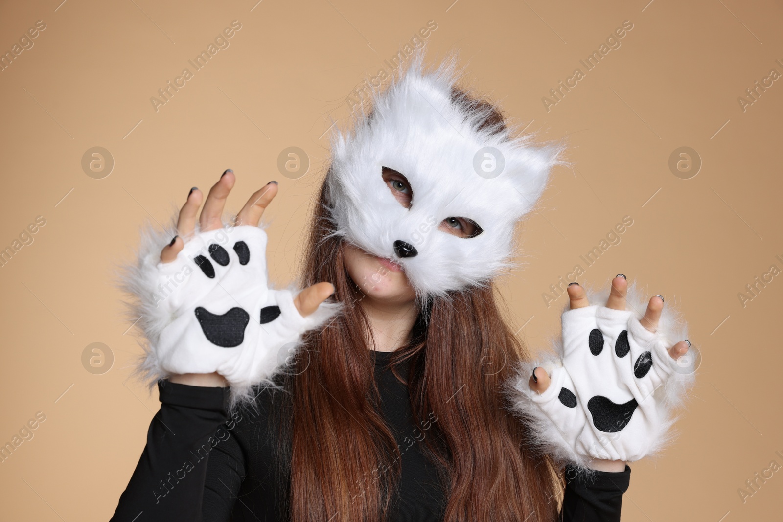 Photo of Quadrobics. Girl wearing cat mask and gloves on beige background