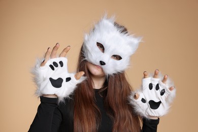 Photo of Quadrobics. Girl wearing cat mask and gloves on beige background